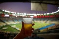 Disposable glass with beer. Soccer stadium on the background Royalty Free Stock Photo