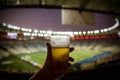 Disposable glass with beer. Soccer stadium on the background Royalty Free Stock Photo