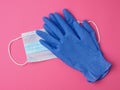 Disposable gloves and medical mask made of non-woven material with white rubber bands on a pink background Royalty Free Stock Photo