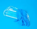 Disposable gloves and stack of medical masks made of non-woven material with white rubber bands on a blue background Royalty Free Stock Photo