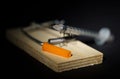 Disposable insulin syringe lying in a wooden mousetrap on a black background.