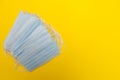 Disposable medical face masks are stacked on a yellow background with copy space Royalty Free Stock Photo