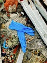 Disposable medical gloves on ground with other plastic trash on landfill. How to dispose used medical gloves right after Royalty Free Stock Photo