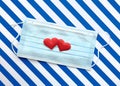 Disposable medical mask on striped blue  white background with red hearts on it against bacteria and viruses. Stop spread of Royalty Free Stock Photo