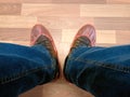 Disposable orange shoe covers on the feet in brown shoes and blue jeans.