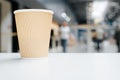 Disposable paper cup of coffee stands on white table in cafe, defocus light background public place, indoors. Royalty Free Stock Photo