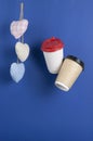 disposable paper flying coffee cups with textile hearts on a blue background hanging on. Takeaway coffee concept. I love coffee Royalty Free Stock Photo