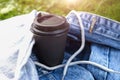 A disposable paper takeaway cup of coffee on the grass in park in summer day, picnic and relaxation on open air