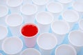 Disposable plastic white empty cups on and one glass filled with red lemonade Royalty Free Stock Photo