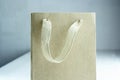 Disposable small craft paper bag for takeaway on white table in the interior. Packaging template mock up. Handle made of natural