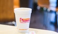 Dunkin donuts cup of hot coffee and sugar sachet on table Royalty Free Stock Photo