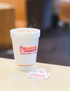 Dunkin donuts cup of hot coffee and sugar sachet on table Royalty Free Stock Photo
