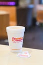 Dunkin donuts cup of hot coffee and sugar sachet on table Royalty Free Stock Photo