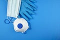 Disposable surgical face masks, white respirator and rubber gloves on blue background