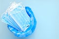 Disposable surgical mask is thrown to the trash bin on a blue background with copy space. Coronavirus and quarantine is Royalty Free Stock Photo