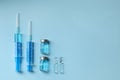 Disposable syringes with needles, ampules and vials on blue background, flat lay. Space for text Royalty Free Stock Photo