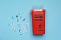 Disposable syringes, needles and sharps container on light blue background, flat lay