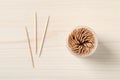 Disposable toothpicks and holder on white wooden background, flat lay