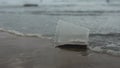 Disposable plastic cup abandoned on the beach dirtying the sea