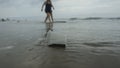 Disposable transparent plastic cup abandoned on the beach dirtying the sea with people walking on the beach in the background