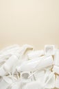 Disposable white plastic tableware on a beige background. The concept of nature pollution. Copy space.