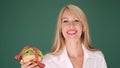 Woman looking at burger and prohibits junk food on green background