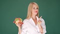 Woman looking at burger and prohibits junk food on green background