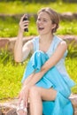 Dissapointed and Angry Young Caucasian Woman Shouting at Her Cellphone. Sitting on the Ground Against Green Grass Royalty Free Stock Photo