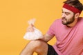 Dissatisfied bearded fitness sporty guy sportsman in headband t-shirt in home gym isolated on yellow background. Workout
