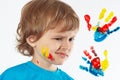 Dissatisfied boy with painted face on background of hand prints Royalty Free Stock Photo