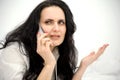 dissatisfied brunette talking on the phone she shows her hand to the side wrinkle her forehead displeasure horror sad