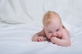 Dissatisfied child on his tummy holds a finger in his mouth. White background Royalty Free Stock Photo