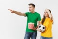 Dissatisfied couple, woman, man, football fans in yellow green t-shirt cheer up support team with soccer ball bucket of