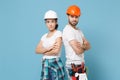 Dissatisfied couple woman man in protective helmet hardhat isolated on blue background. Instruments accessories
