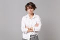 Dissatisfied displeased young business woman in white shirt posing isolated on grey wall background in studio