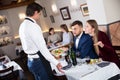 Dissatisfied family couple talking to apologetic waiter