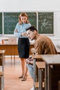 Dissatisfied female teacher with arms crossed looking at male student cheating during exam Royalty Free Stock Photo