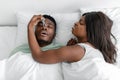 Dissatisfied funny millennial black lady wake up from snoring sleeping man, closes his nose with clothespin Royalty Free Stock Photo