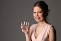 Dissatisfied girl with glass of water. Close up. Gray background Royalty Free Stock Photo