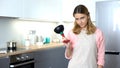 Dissatisfied housekeeper showing plunger, tool to unclog drain, plumber service