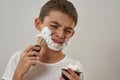 Dissatisfied little boy smear shaving foam on face