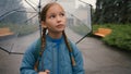 Dissatisfied little girl city street outside bad weather rain schoolgirl with umbrella learner school unhappy child kid Royalty Free Stock Photo