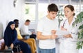 Dissatisfied surprised young man discussing documents with a doctor in the lobby of medical clinic Royalty Free Stock Photo