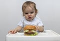 Dissatisfied toddler kid looking at a big burger Royalty Free Stock Photo