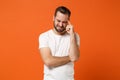 Dissatisfied upset young man in casual white t-shirt posing isolated on orange background studio portrait. People Royalty Free Stock Photo