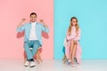 dissatisfied woman with arms crossed and cheering man with clenched fists sitting on chairs