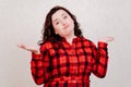 dissatisfied woman in red dress on white background spreads hands to sides.