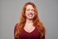 Dissatisfied woman with red hair making a grimace