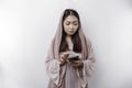 A dissatisfied young Asian Muslim woman looks disgruntled wearing a hijab irritated face expressions holding her phone Royalty Free Stock Photo