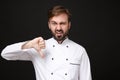 Dissatisfied young bearded male chef cook or baker man in white uniform shirt posing isolated on black wall background
